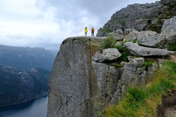 Preikestolen (Prekestolen, Pulpit Rock) is a famous tourist attraction near Stavanger, Norway.  Preikestolen is steep cliff which rises above Lysefjord. Couple is standing on cliff.