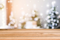 abstract blurry beautiful of decoration Christmas tree in sweet house with snowfall effect background  and plank wooden texture floor for show, advertise, promote product concept