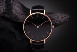 
A luxury gold watch with a black dial. A watch on a beautiful stand, on a beautiful lightly lit gray background. Woman/Man fashion