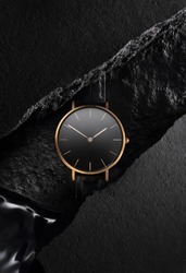 Luxurious gold watch with a black dial. A watch on a beautiful black background with black stones. Women's, Men's fashion