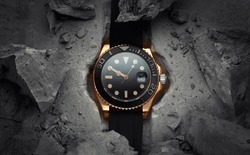 A beautiful luxury men's gold watch built into or embedded in a rock or stone. Stylish golden watch on a beautiful background of stones or rocks. Advertising photo of the watch
