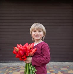Cute boy 4-5 years old with a bouquet of red tulips. mothers Day. International Women's Day. Spring holiday mood. Flowers for mommy, girlfriend