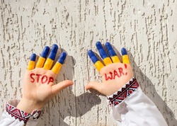 hands of a child in national clothes, painted in yellow - blue, the inscription STOP WAR. Russia's invasion of Ukraine, Children against the war. Military conflict with Russia.. Stand with Ukraine