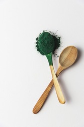 Wooden spoons with spirulina powder, superfood on a white background, vertical, full spoon