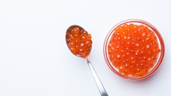 Salmon Red Caviar. Red fish caviar on a spoon in glass bowl. Raw seafood. Luxury delicacy food. White background. Flat lay, top view, copy space. 