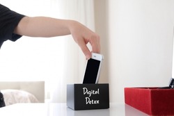 Digital detox concept photo. Woman rejecting social media addiction puts phone in box