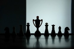 Business strategy conceptual photo – Silhouette of trophy stand in office table with chess pawn