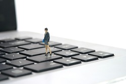 Miniature people toy figure photography. A businesswoman standing above notebook laptop keyboard. Isolated on white background. Image photo