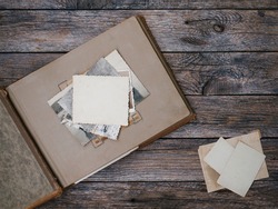 Clear blank photo frames to placed your pictures or text on old family album on wooden board background in retro style. Family traditions, memories and nostalgia concept. Antique album with old photos