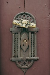 Vintage antique door handle on the old wooden door. Copper keyhole decorative element on weathered wood surface. Architecture in Slovakia. Details of ornate vinous entrance. Focus on doorhandle.
