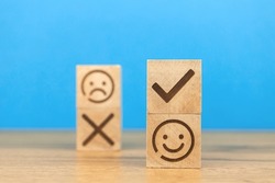 Customer choose positive smiley face and blurred sad face icon on a wooden cubes. Concept of service rating, satisfaction, business marketing background 