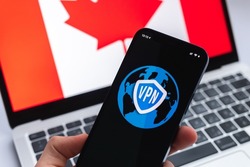 VPN in Canada. Secure and safe internet concept. Privacy. Hand with mobile phone and VPN application. Flag and laptop on the background photo
