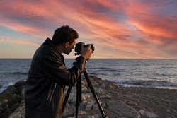 Travel photographer with digital camera making photo of the nature at sunset