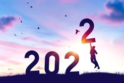 Man jumping on sunset sky with birds flying at top of mountain and number like 2022 abstract background. Happy new year and holiday concept. Vintage tone filter effect color style.