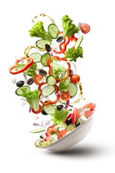 flying salad isolated on white background. Greek salad: red tomatoes, pepper, cheese, lettuce, cucumber, olives and olive oil
