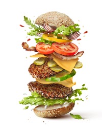 Delicious monster burger with flying ingredients isolated on white background