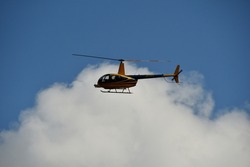 A light helicopter during a technical test flight of a high-voltage power line with a thermal imaging camera mounted in the bow.