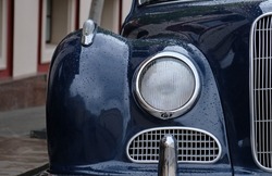 Close-up view of old-fashioned blue retro car. Close-up of old-fashioned round headlights, bumper and hood on a vintage car.