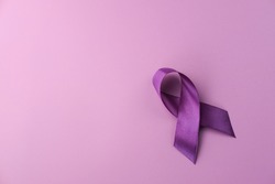 Purple ribbon as symbol of Cancer Awareness Month (World Cancer Day) over purple color background, copy space.
