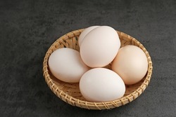 Fresh chicken eggs ( Telur Ayam Kampung ). White eggs served in bamboo plate with copy space. Selective focus image.
