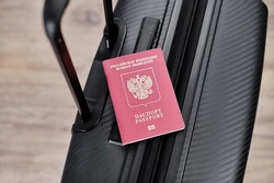 Russian passport on a black travel suitcase, top view, selective background. Emigration of Russians, seeking asylum