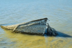 Old abandoned boat, sunken near the shore, sunken or abandoned boat near the sea. Water pollution, environmental problems and garbage pollution