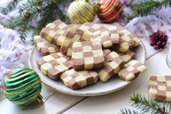 Delicious dessert for a snack for the whole family: chess cookies on a large plate on a white background. Vanilla cookies with chocolate for breakfast. Close-up
