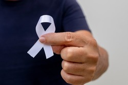White January, mental health awareness campaign. fingers holding white ribbon. 