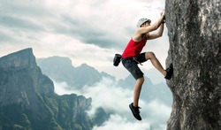 Asian man rock climber in black pants climbing on the cliff.
