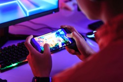 Gamer playing online game on smart phone in dark room. e-Sport Games compilation and Internet Championship.