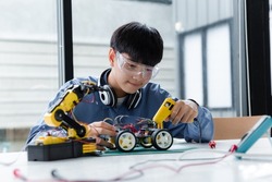 Asian teenager doing robot project in science classroom. technology of robotics programing and STEM education concept.