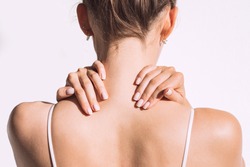 Closeup shot of woman from back having neck or shoulder pain. Injury or muscle spasm. Back and spine disease. Female massaging her neck. Health care and medical concept