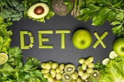 Top view of fresh green vegetables and fruits with word detox on a black background. Detox diet, clean and healthy eating