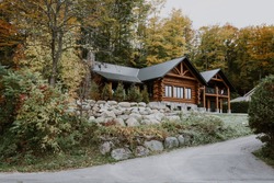 Wooden mountain house built from wood logs. Beautiful log house with porch, patio and driveway in peaceful forest scenery, Canada
