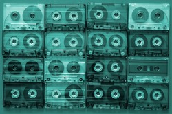 80s music on audio cassettes. Many audio tapes with old songs. Stained audio cassettes background. Tinted photo.