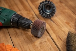 Electric drill, flap wheel, knot bowl wire disk, metal brush against the wooden background. Electric and hand tools for woodworking. Indoors. Selective focus.