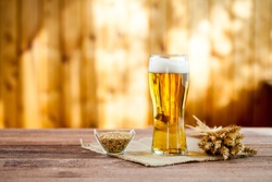 glass of beer with wheat on a wooden table background