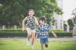 Cute Asian children runing together in the park outdoors