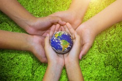 Earth planet in asian Children hand on green grass background. - Elements of this image furnished by NASA