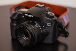 Canon eos 60d camera. The camera and a lens on a black bakcground