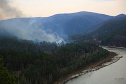 in the taiga forest near the river a fire burns and smokes