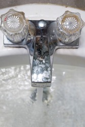 Running faucet splashing water in dirty grimey gross nasty disgusting wash sink. Bathroom Kitchen sink faucet running water splash. Clogged wet water wash basin in grunge stains smudges on chrome tap.