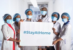 Group of African women nurses activists in face mask, hand sign plackard, caption hashtag StayAtHome. Group of medics, message for social media. Information alert to stay at home to flatten the curve.