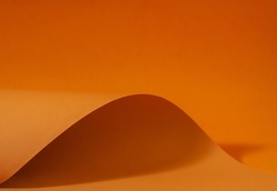 Orange and brown paper is curved by a wavy line, beautiful soft light and shadow on paper, abstract background for designers.