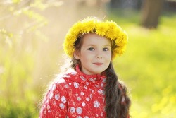 Portrait of a cute girl in a wreath of dandelions, spring mood, happy child outdoors.
