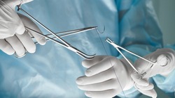 Close up of surgical team hands, surgeon holding needle holder and suture material. Suture thread. Nylon surgical thread. Needle holer and suture material in operating room,medical concept.