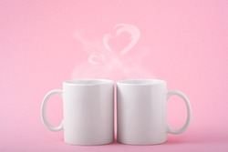Mockup white coffe two cups or mug on a pink background with copy space. Blank template for your design, branding, business. Real photo. Hot drink steam in the form of hearts