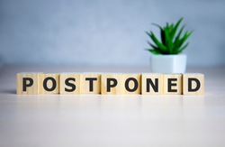 Postponed - words from wooden blocks with letters, postponed concept, top view background