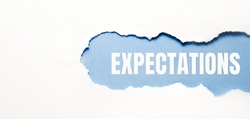 inscription Expectations word on blue torn papper.