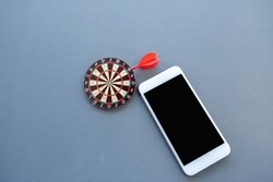The small dartboard and the arrow located with telephone represent successful business goals concept.
